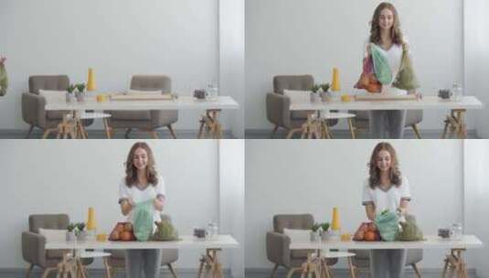 年轻微笑的女人把装有水果和蔬菜的袋子放在现代办公室的桌子上高清在线视频素材下载