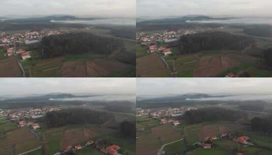 空中拍摄的村庄中间的树木和草地与雾。高清在线视频素材下载