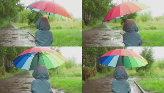孩子带着阳伞在雨中公园漫步高清在线视频素材下载