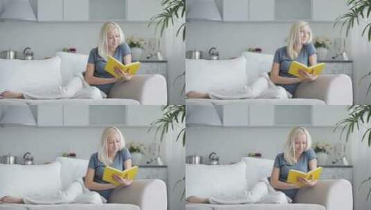 年轻女子坐在沙发上看书 高清在线视频素材下载