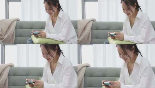 一位年轻女士在沙发上用手机打游戏高清在线视频素材下载