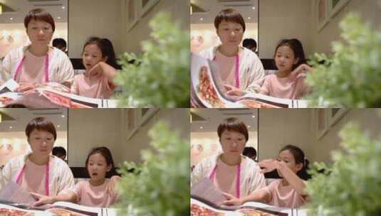 认真看着菜谱点菜的中国女孩和母亲高清在线视频素材下载