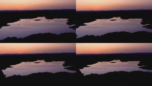 天空在平静光滑的湖面上，紫色的反射光映衬着橙色的日落天空高清在线视频素材下载