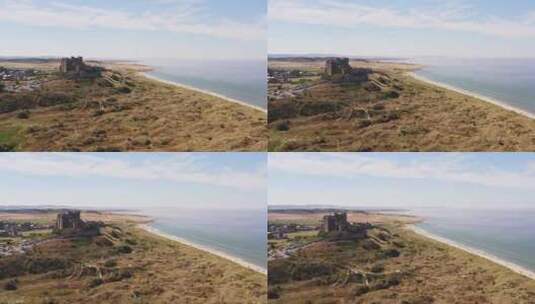 空中拍摄升起沙丘，露出海边一座美丽的城堡，度假者在上面高清在线视频素材下载