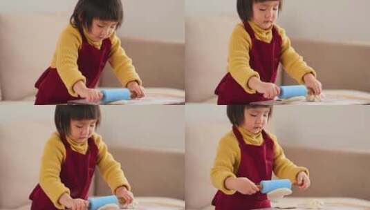 小女孩在家里用擀面杖揉面玩过家家的游戏高清在线视频素材下载