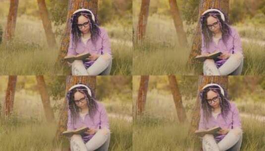 戴眼镜耳机的女子在树旁看书高清在线视频素材下载