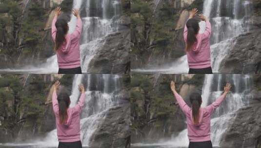 亚洲中国人女性在瀑布下张开双臂拥抱自然高清在线视频素材下载