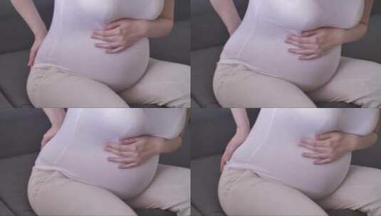 沙发上摸着孕肚疼痛的孕妇高清在线视频素材下载