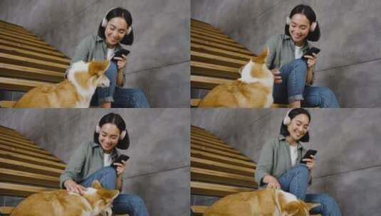 女人微笑着坐在楼梯上听音乐摸着狗高清在线视频素材下载