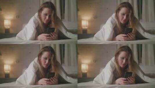 女人看着躺在床单下的手机高清在线视频素材下载