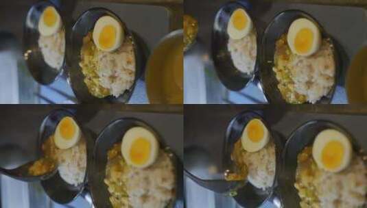 奶油豆腐咖喱舀进黑色碗里，里面有鸡蛋和米高清在线视频素材下载
