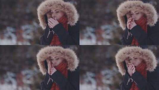 穿着冬衣并用手呼吸以在户外保暖的妇女高清在线视频素材下载