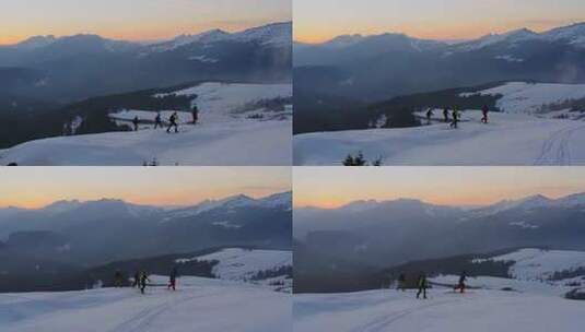 日落时分，一群滑雪旅行徒步旅行者攀登罗尔山口积雪覆盖的山峰。空中高清在线视频素材下载