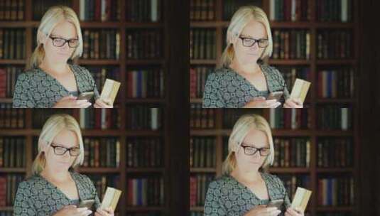 女士在图书馆看手机高清在线视频素材下载