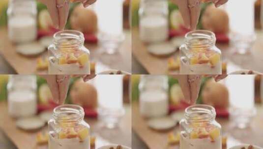女人在厨房的小玻璃罐里给酸奶添加水果和坚高清在线视频素材下载