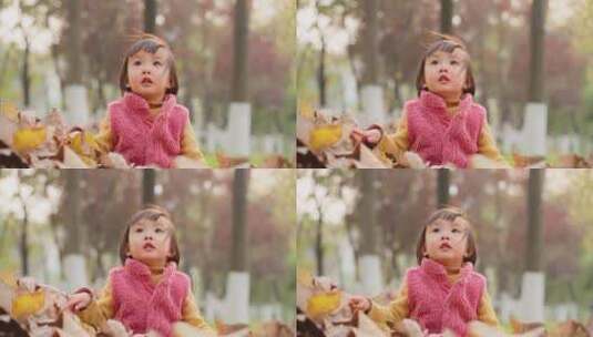 秋天可爱小女孩坐着树叶堆上玩耍高清在线视频素材下载
