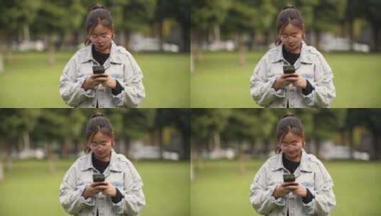 年轻女孩在公园里看手机高清在线视频素材下载