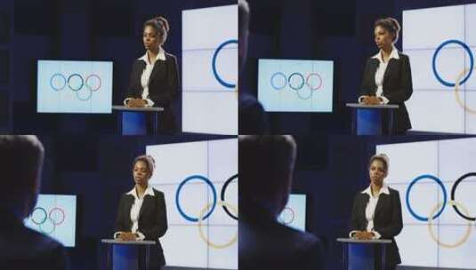 非裔美国主播在奥林匹克标志前阅读奥林匹克新闻，向左摇向一个制作团队高清在线视频素材下载