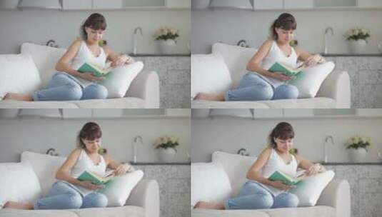 漂亮的年轻女人在沙发上读书高清在线视频素材下载