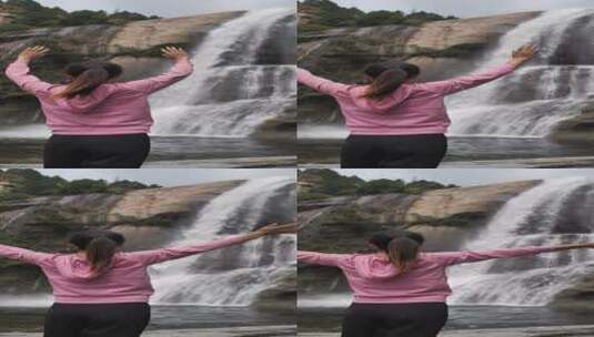 亚洲中国人女性在瀑布下张开双臂拥抱自然高清在线视频素材下载