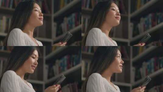 亚裔女女少数民族女学生在大学图书馆书架上高清在线视频素材下载