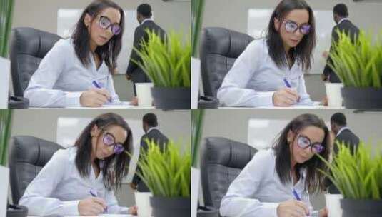 坐在办公桌前在纸上写字的女人高清在线视频素材下载