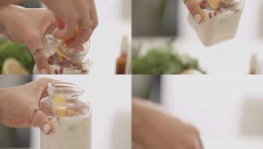 女人在厨房的酸奶罐里添加了大块水果高清在线视频素材下载