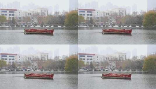 冬天初雪大雪纷飞，湖泊上漂浮红船高清在线视频素材下载
