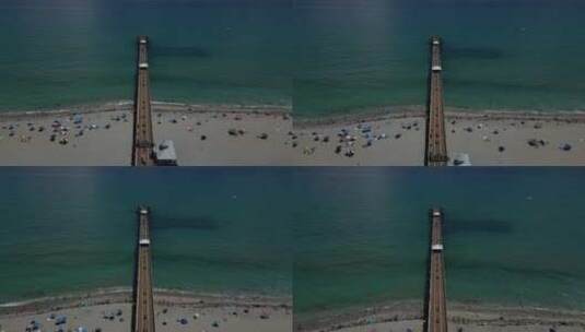 空中无人机镜头，多莉镜头和海滩上有人的长延伸码头。对称高清在线视频素材下载