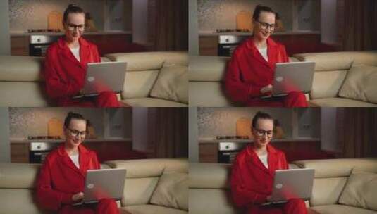 晚上穿着红色睡衣在家用笔记本电脑工作的女高清在线视频素材下载