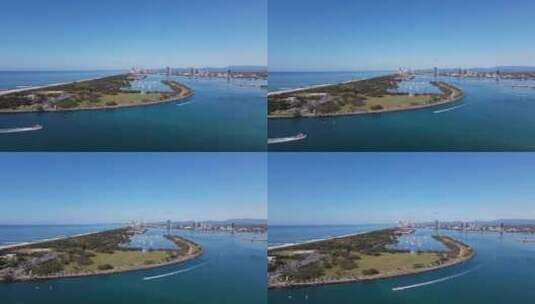 高空腹无人机视图在一个人造海洋入口上空向一个城市船港移动高清在线视频素材下载