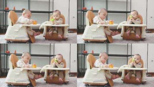 双胞胎宝宝坐在椅子里玩耍高清在线视频素材下载