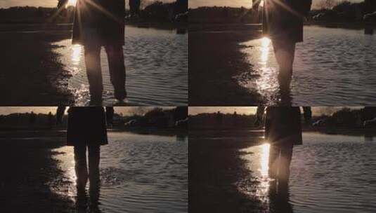 日落时在水坑中溅起水花的人的剪影高清在线视频素材下载