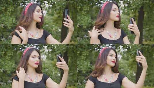 一名年轻的高加索妇女整理头发，用智能手机当镜子高清在线视频素材下载