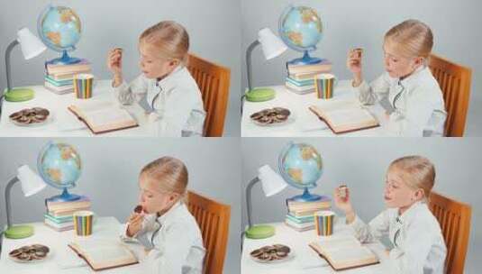 女生坐在书桌旁边吃巧克力边读书高清在线视频素材下载