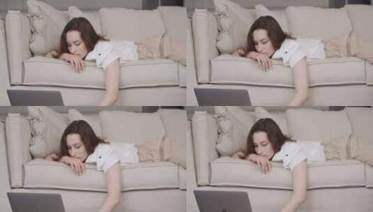女孩躺在沙发上在电脑上打字高清在线视频素材下载