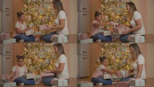 小女孩和女人在圣诞树旁交换礼物高清在线视频素材下载