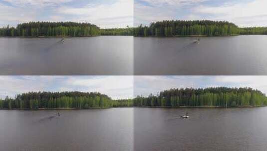 鸟瞰被森林包围的湖泊，两名渔民在船上捕鱼高清在线视频素材下载