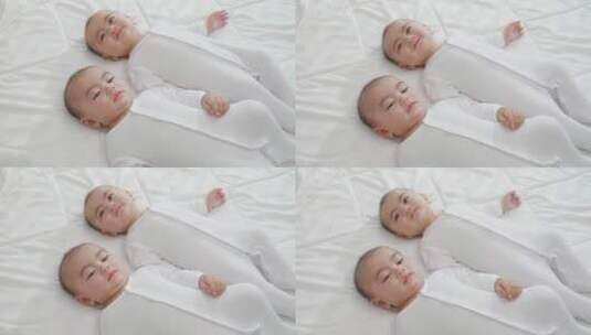 双胞胎宝宝靠在床上玩耍高清在线视频素材下载