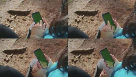 女子使用智能手机的肩上照片，绿屏模糊自然高清在线视频素材下载