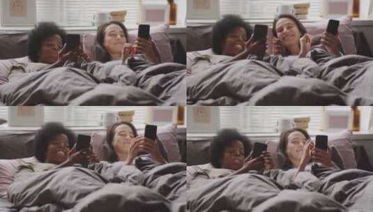 两个女人躺在床上看着手机大笑高清在线视频素材下载