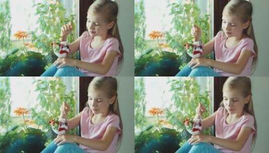 女孩坐在窗台上吃冰淇淋并微笑点头高清在线视频素材下载