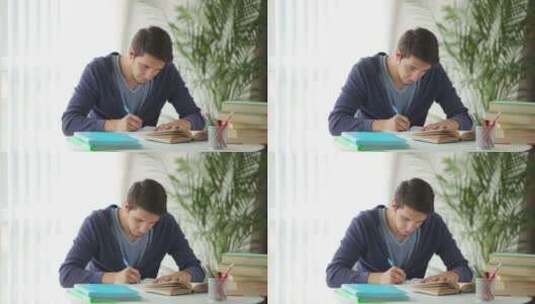 帅哥坐在桌旁学习和写笔记高清在线视频素材下载