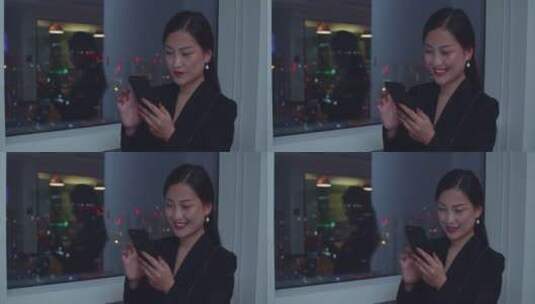 职场女性在办公室窗边用手机浏览网络高清在线视频素材下载