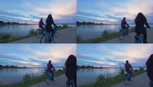 夫妇在日落时沿着水面骑自行车高清在线视频素材下载