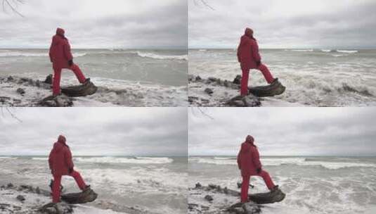 身着温暖红色衣服的女孩站在北方暴风雨大海的岸边高清在线视频素材下载