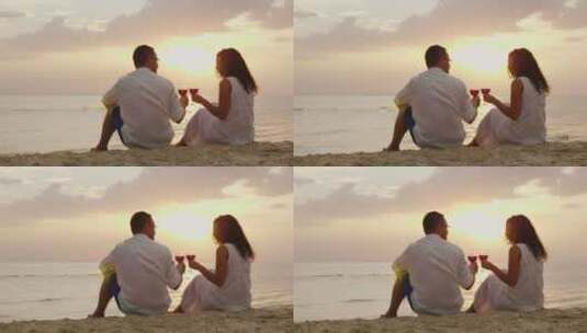 一对年轻夫妇坐在沙滩上喝酒高清在线视频素材下载