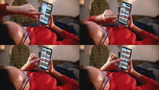 躺在床上的一名男子在手机上滚动食物图片高清在线视频素材下载