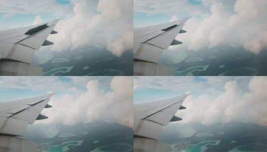 飞机机翼的慢动作，从飞机照明中看到云和岛高清在线视频素材下载