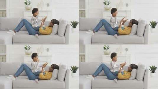 母亲和儿子躺在沙发上玩耍高清在线视频素材下载